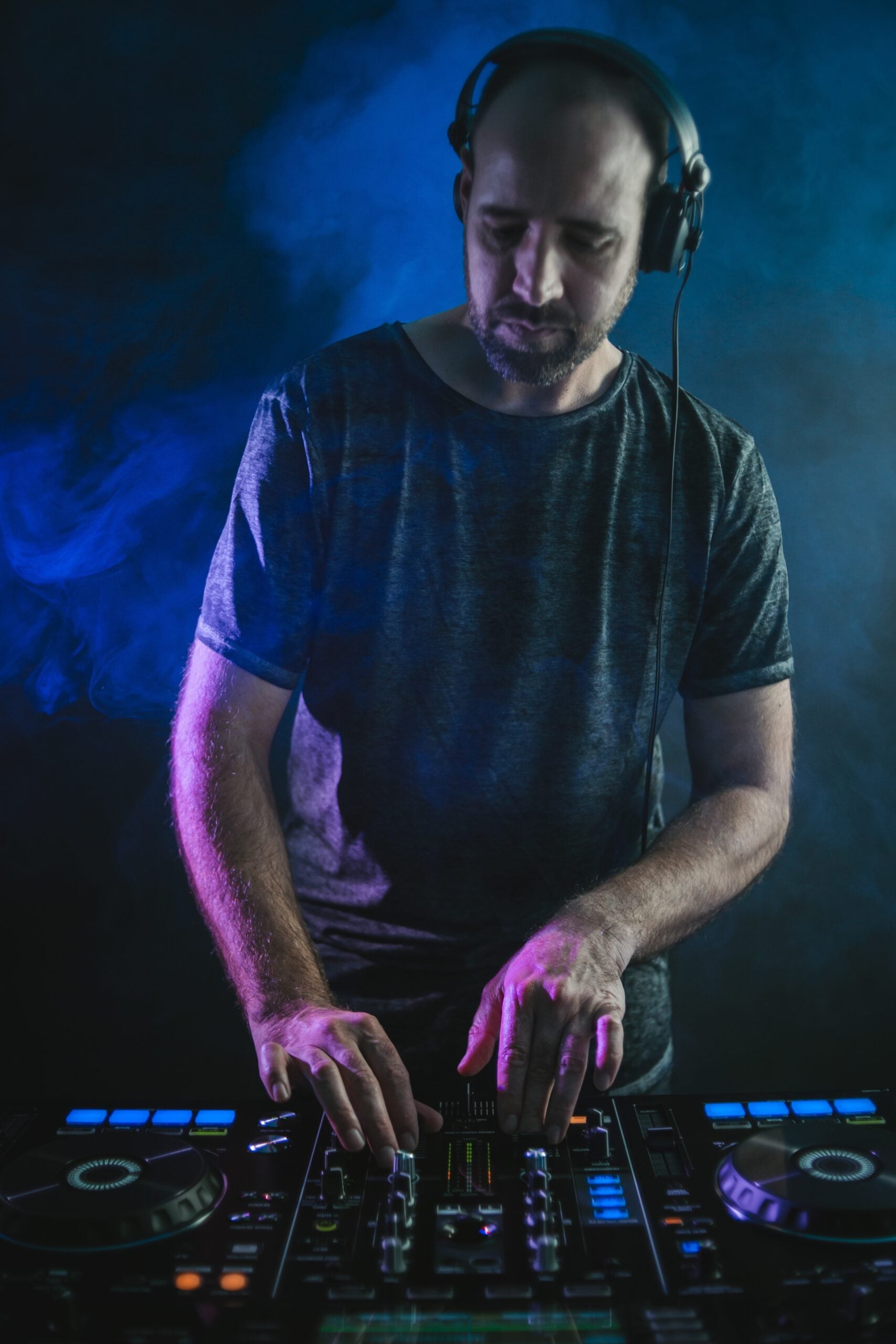 Vertical picture of a Male DJ under the blue lights and smoke in a studio