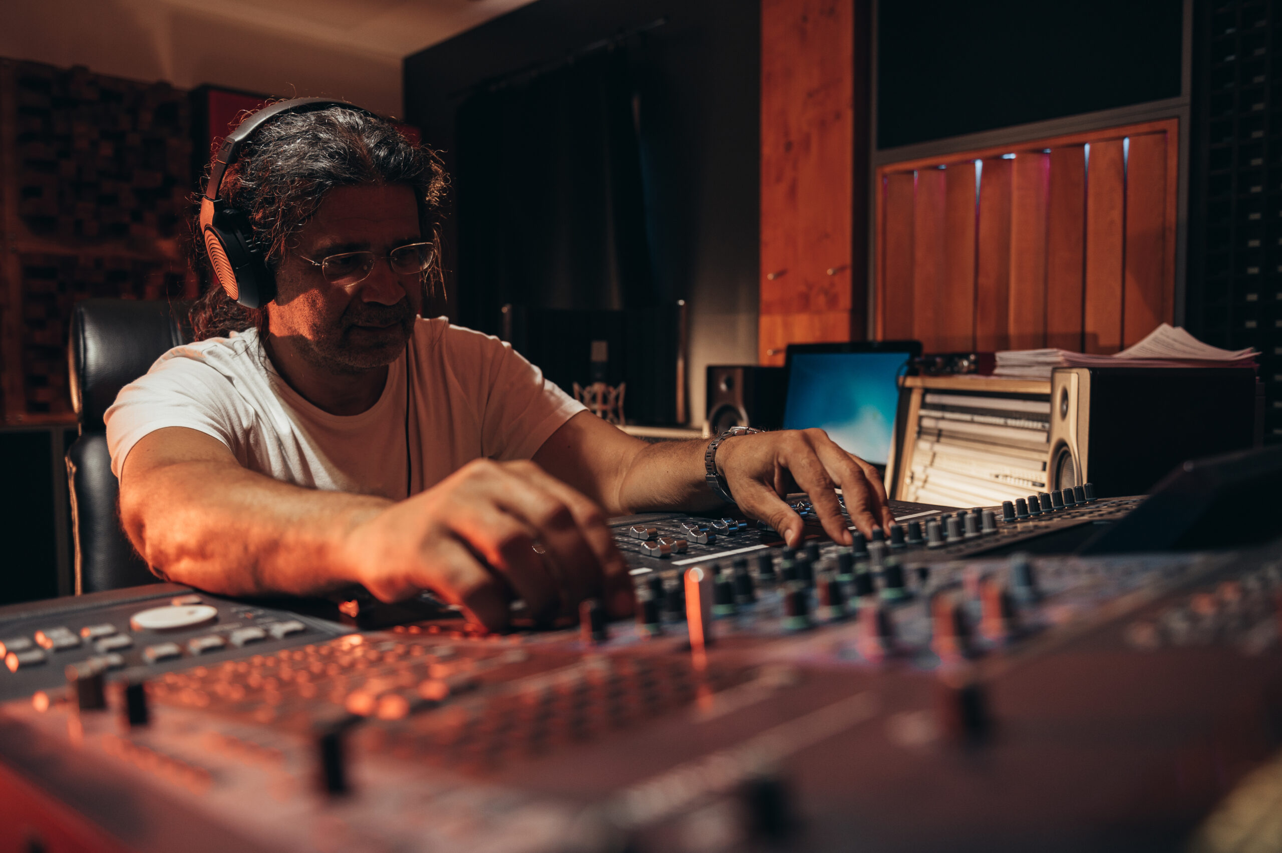 Senior hispanic music producer working on a mixing soundboard wh