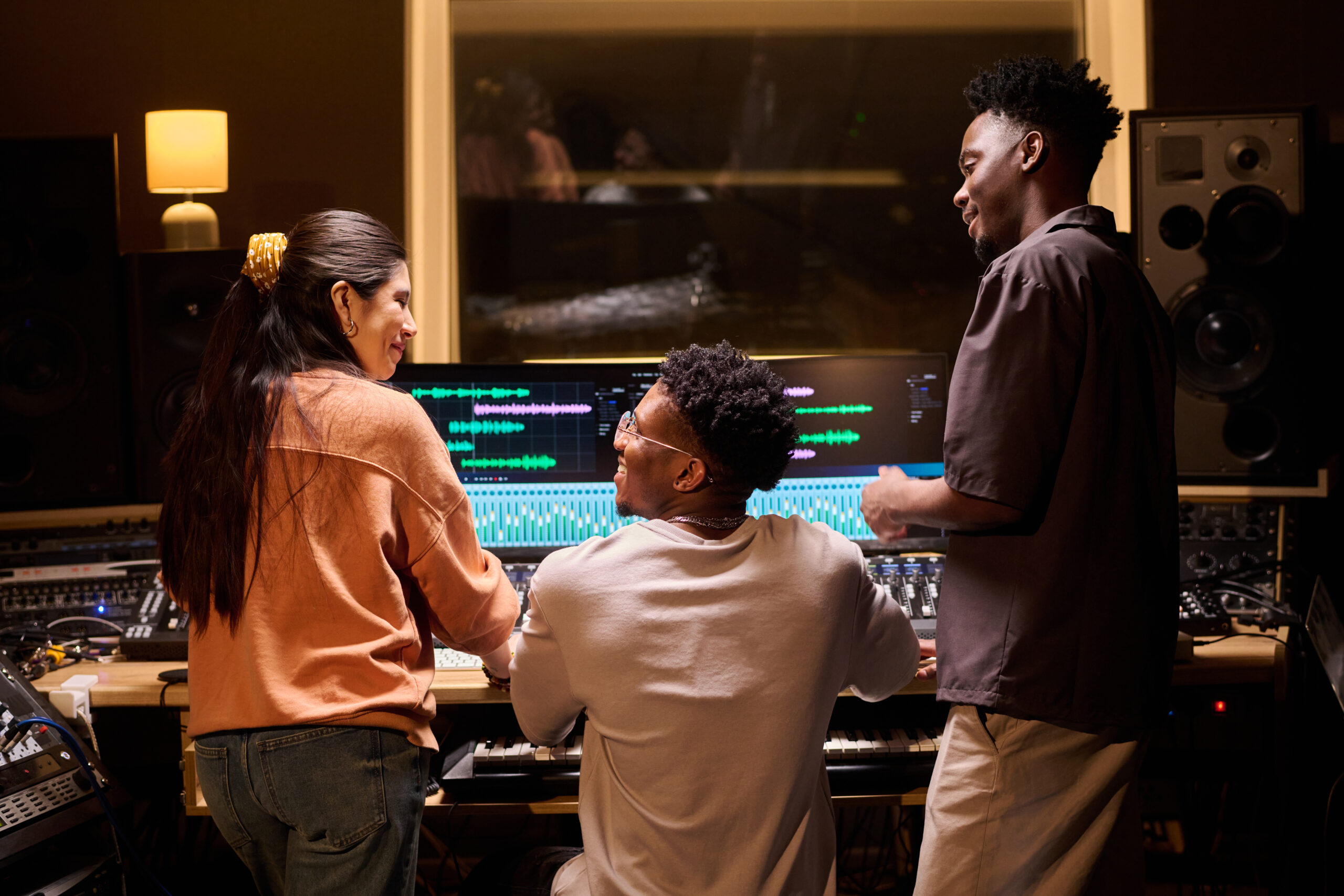 Young Multiethnic Adults Smiling While Producing Music at Audio Workstation